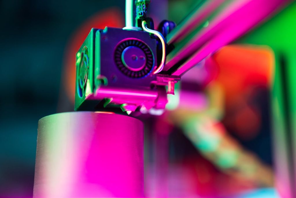 pexels-photo-31137471 Close-up of a 3D printer in action under neon lighting, capturing vibrant colors and modern tech ambiance.