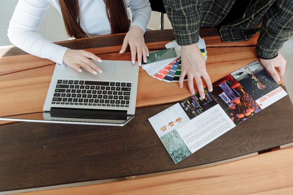pexels-photo-7180492 Two colleagues working on a design project using a laptop and color guides at a wooden table.