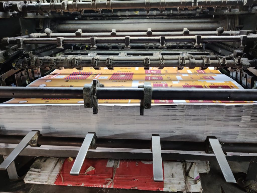 pexels-photo-9550363 Close-up of an industrial printing machine processing paper sheets in a factory setting.